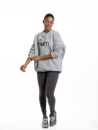 Model in FRDM Core Jumper sweatshirt using Freedom Refresh Wipe, premium women’s athleisure.